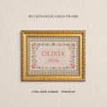 The image is a gold-framed cross-stitch print titled "OLIVIA Avery" with a floral border. The text "BUCKHAM GOLD FRAME" is displayed above the print, and the phrase "Cross-stitch Aesthetic - Printed art" is at the bottom of the image.