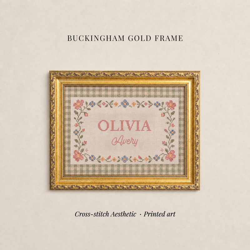 The image is a gold-framed cross-stitch print titled "OLIVIA Avery" with a floral border. The text "BUCKHAM GOLD FRAME" is displayed above the print, and the phrase "Cross-stitch Aesthetic - Printed art" is at the bottom of the image.