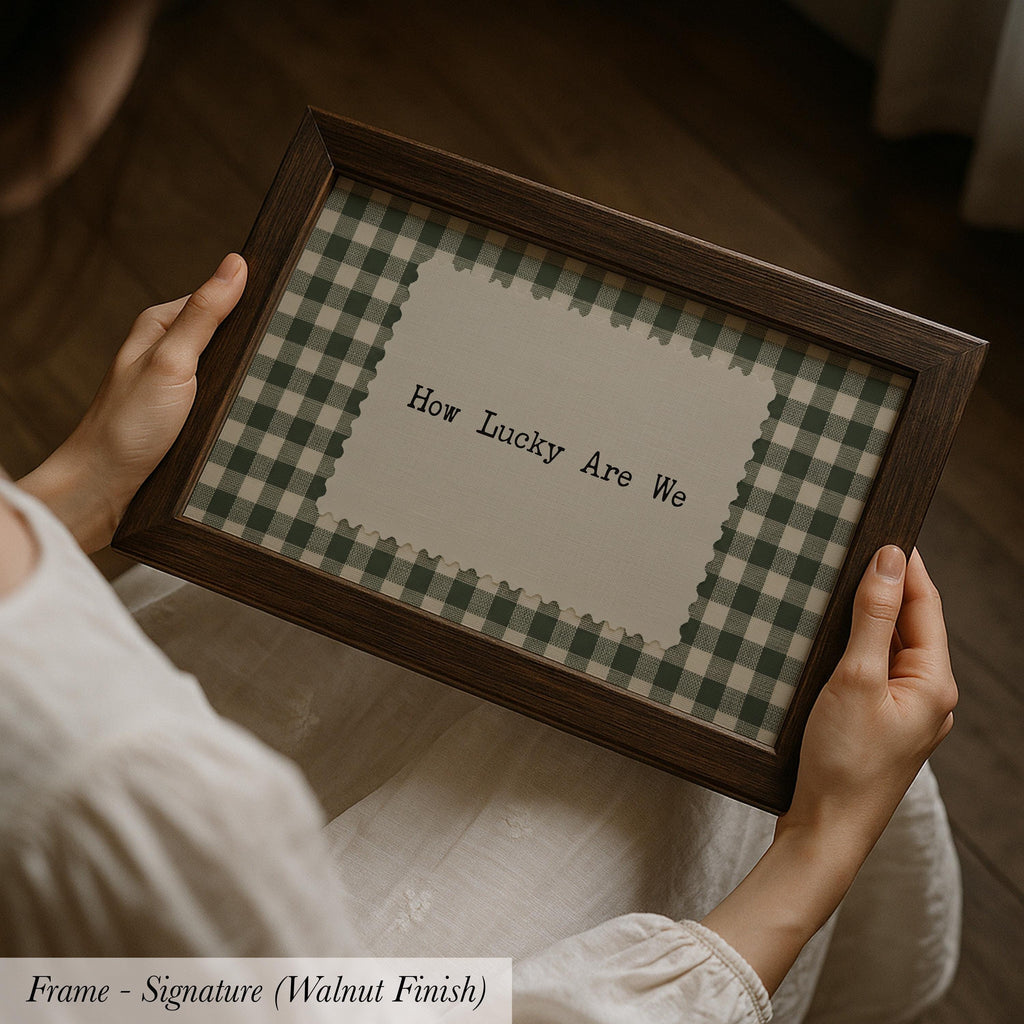 A person is holding a framed picture with the text "How Lucky Are We" on it.