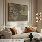 a living room with a white sofa, a framed artwork depicting a tree, and a lamp on a side table.