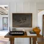 a wooden table with a black keyboard, a white vase, and a book, along with a framed quote that reads "How lucky are we".