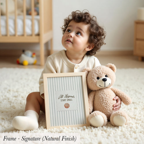 A young child sits on the floor, holding a picture frame with a teddy bear inside.