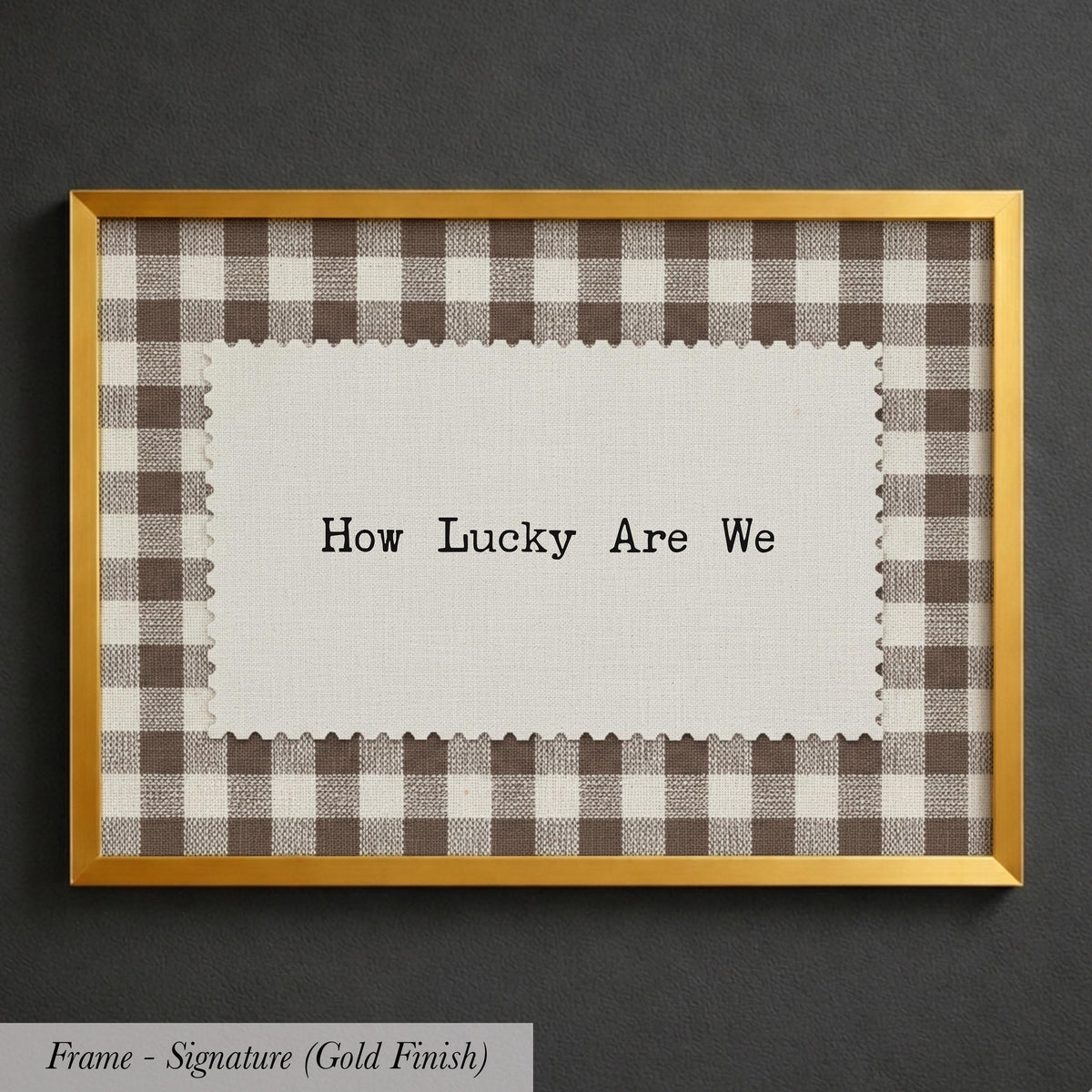 A framed piece of paper with the text "How Lucky Are We" written on it, placed inside a gold-framed picture.