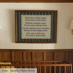 a framed nursery wall with a poem or lyrics about a little boy, including a message about holding him longer, telling him a story, letting him sleep on his shoulder, and cheering him on.