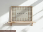 A wooden shelf with a framed picture on it, displaying the text "How Lucky Are We" in a checkered pattern.