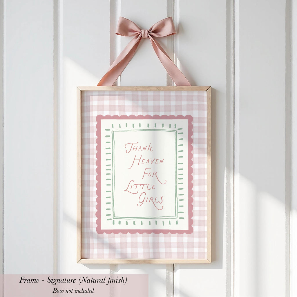 A framed sign with a pink bow hanging on a white wall.