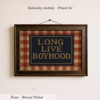 a framed embroidered design with the text "LONG LIVE BOYHOOD" on a plaid background.