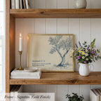 A framed print of a tree with a quote from Jeremiah 7:8 is displayed on a wooden shelf, accompanied by a white vase with flowers, a candle, and some books.