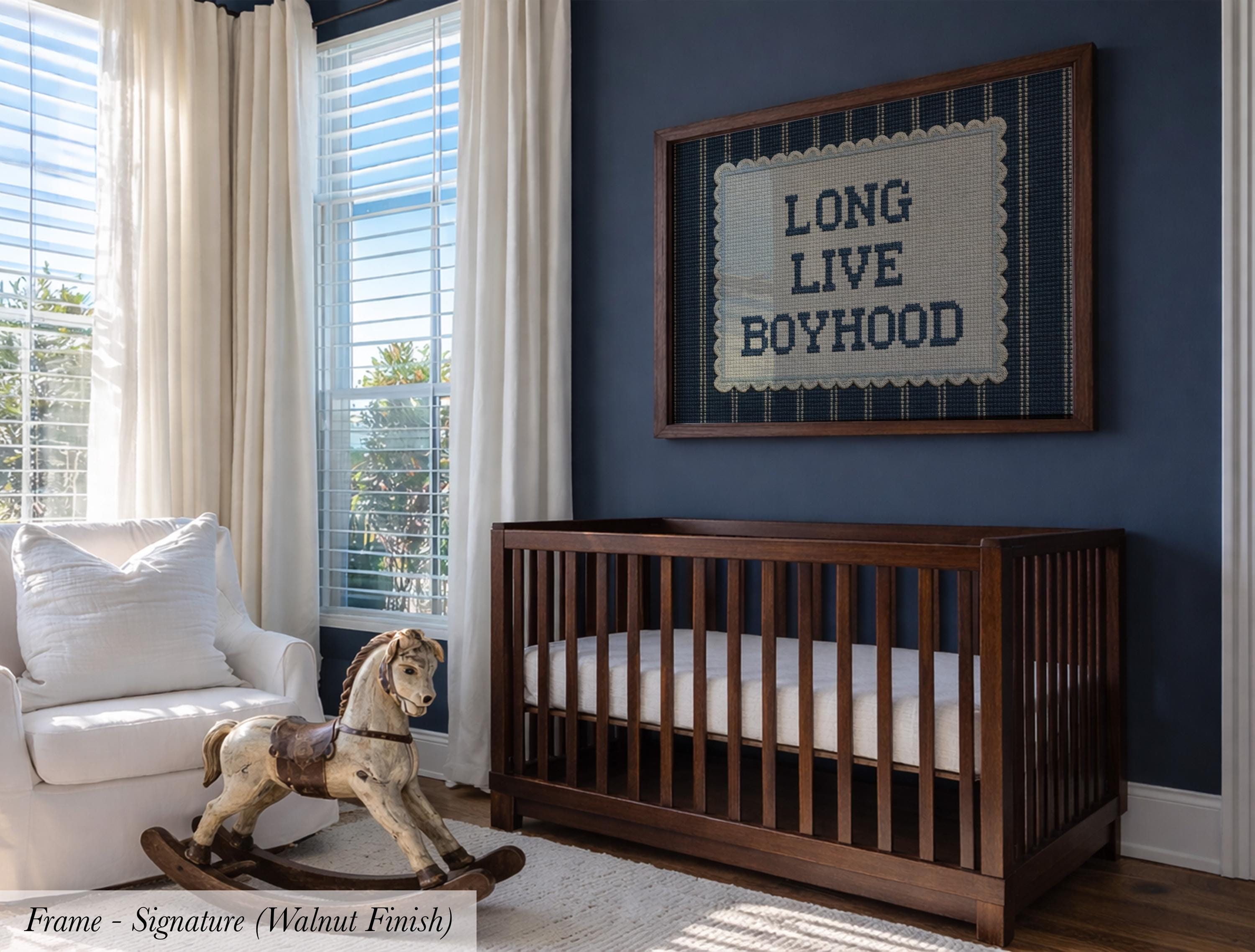 a nursery room with a wooden crib, a rocking chair, and a framed sign on the wall that reads "LONG LIVE BOYHOOD".