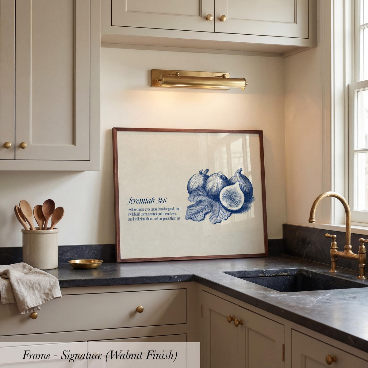 A framed print of a blue and white illustration of figs is displayed on a kitchen counter, accompanied by a quote about faith and trust.