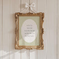 a gold-framed picture with a white border hanging on a white wooden wall. The picture contains a message that reads "YOU'LL NEVER KNOW DEAR HOW MUCH I LOVE YOU".