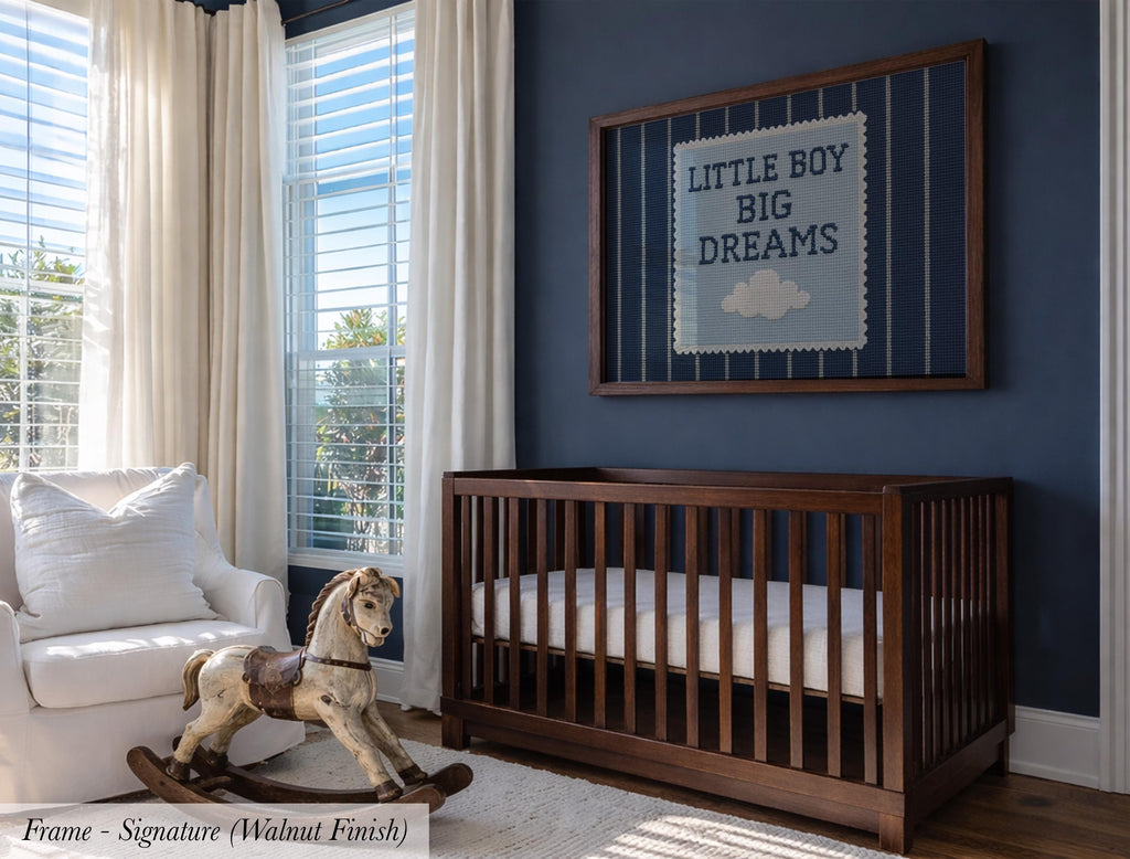 A wooden crib with a white mattress, a rocking horse, and a framed sign with the text "Little boy big dreams" on a blue wall.