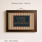 a framed embroidered piece of art with the text "LONG LIVE BOYHOOD" displayed on it.