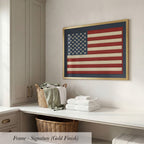 a framed American flag hanging on a wall above a white countertop with folded towels and a wicker basket.