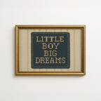 a framed cross-stitch design with the text "LITTLE BOY BIG DREAMS" displayed on it.