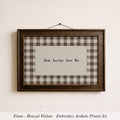A framed piece of embroidered artwork with the text "How Lucky Are We" displayed on it.
