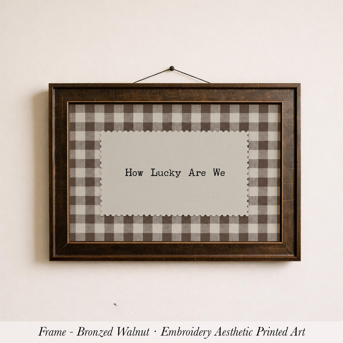 A framed piece of embroidered artwork with the text "How Lucky Are We" displayed on it.