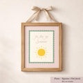 A framed picture with a pink and white striped border, featuring a yellow sun and the text "You are my sunshine" written in cursive.