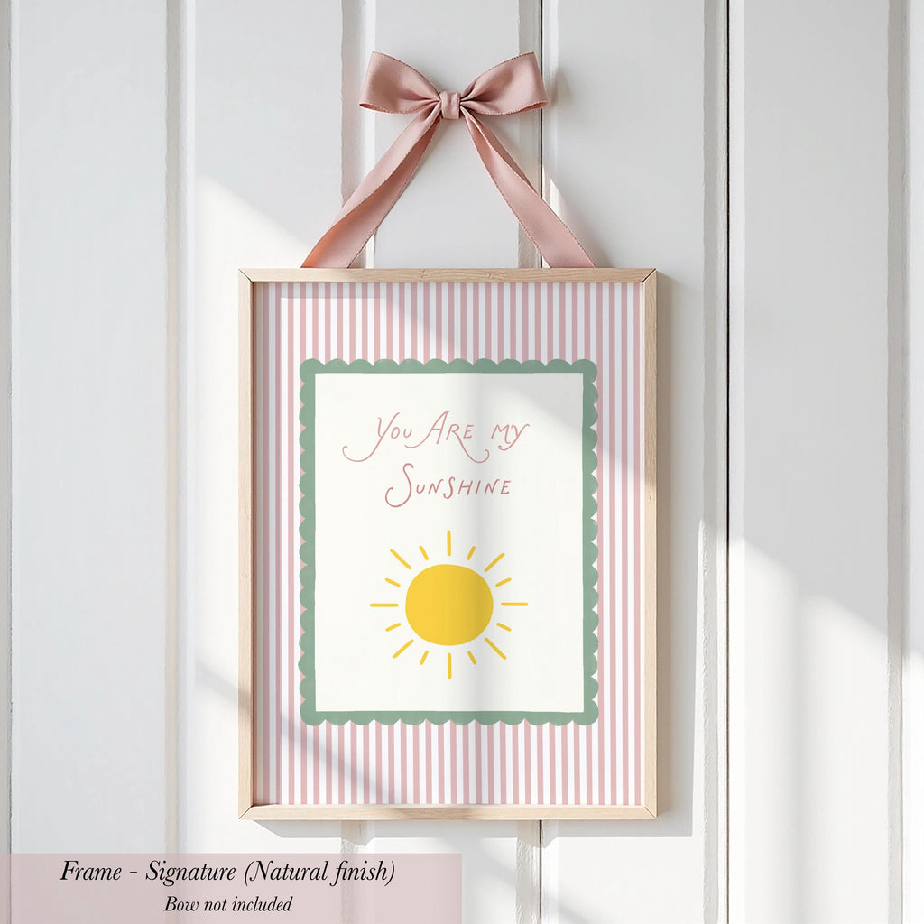 A framed picture with a pink ribbon and a message that says "You are my sunshine".