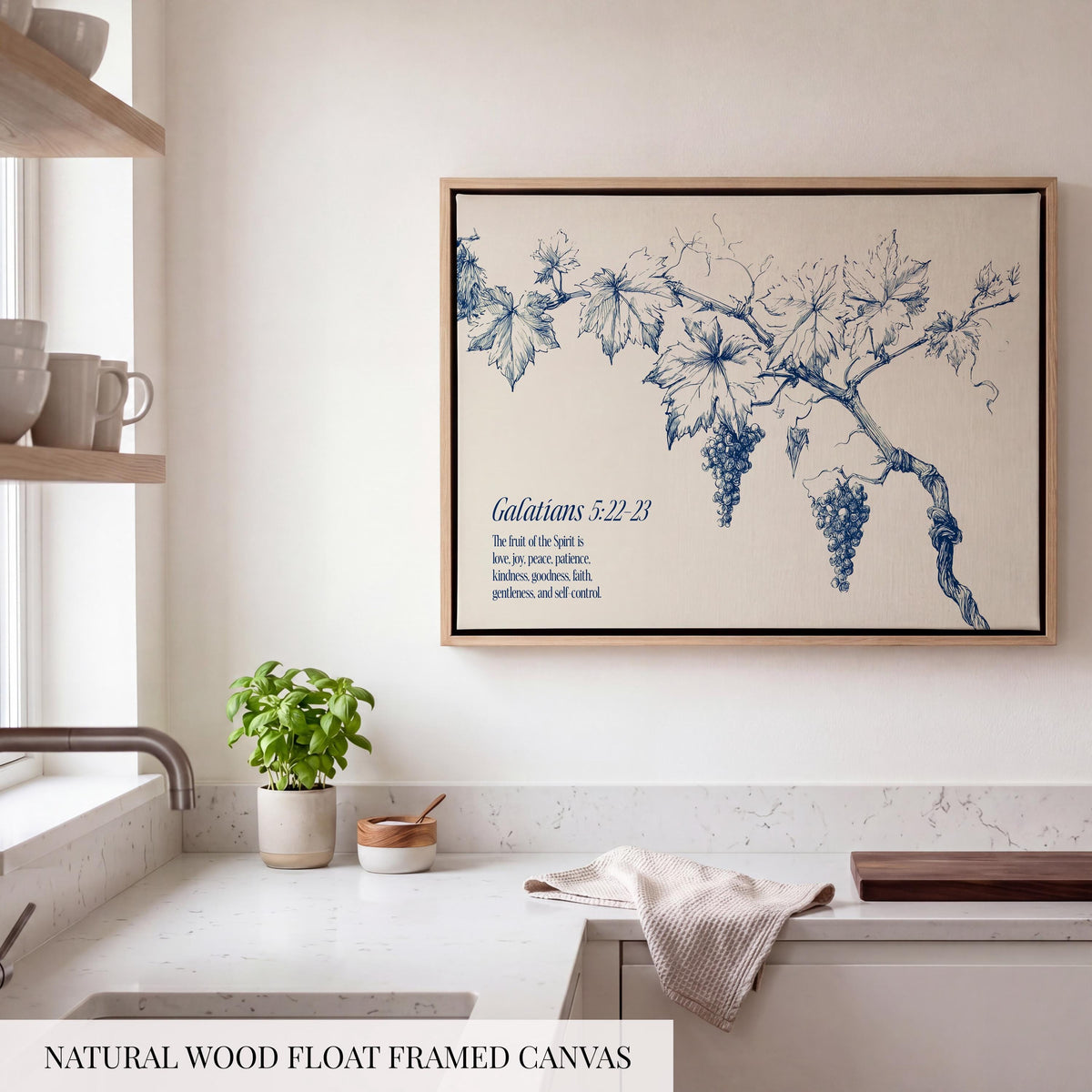 a kitchen counter with a potted plant, a wooden cutting board, and a framed canvas depicting a blue and white illustration of grapes and leaves.