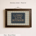 a framed embroidered design with the text "LONG LIVE BOYHOOD" on it.