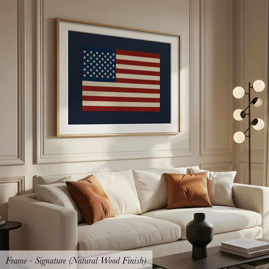 a living room with a white sofa, a framed artwork of the American flag, and a lamp on a side table.