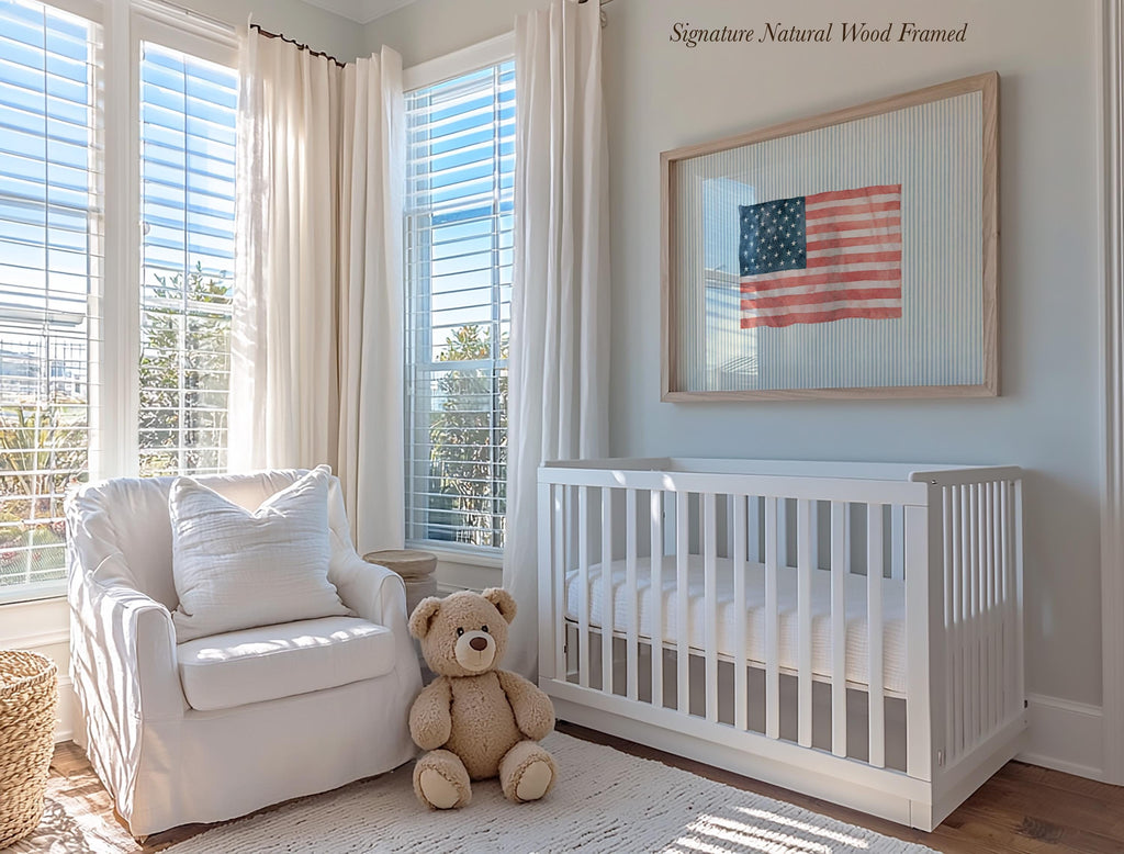 A cozy nursery with a white crib, a white chair, and a teddy bear. The room has large windows that let in natural light, and a framed American flag is displayed on the wall.