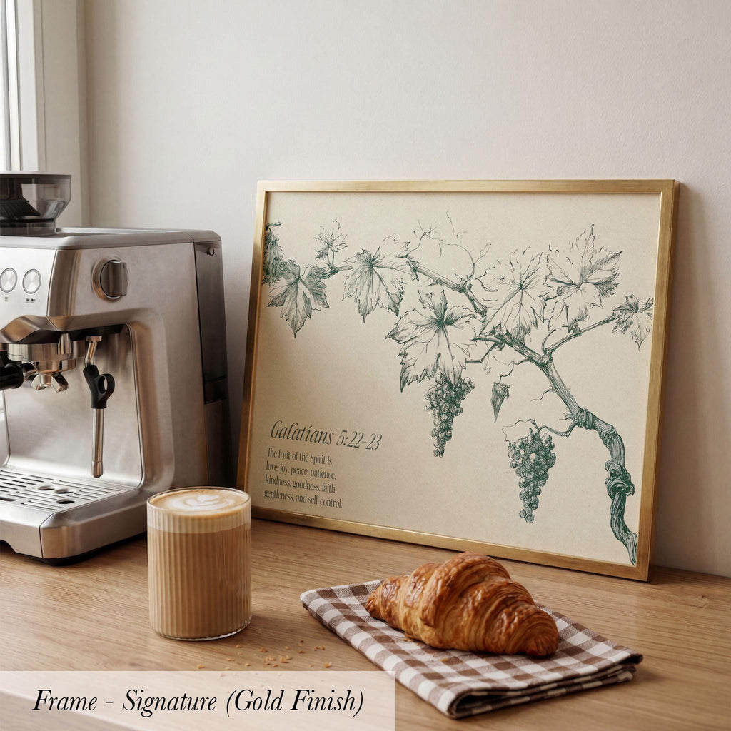 a framed print of a vineyard scene with grapes and leaves, a croissant, a cup of coffee, and a coffee maker on a wooden countertop.