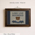 The image is a framed embroidery depicting a bear with mountains in the background, accompanied by the text "LONG LIVE BOYHOOD".