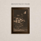 The image is a framed photograph of a flower with a butterfly in flight, mounted on a wall.