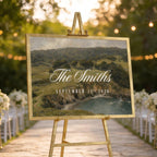 a wedding ceremony setup with a large sign displaying the names of the couple and the date of their wedding, surrounded by white chairs and a scenic outdoor setting with trees and string lights.