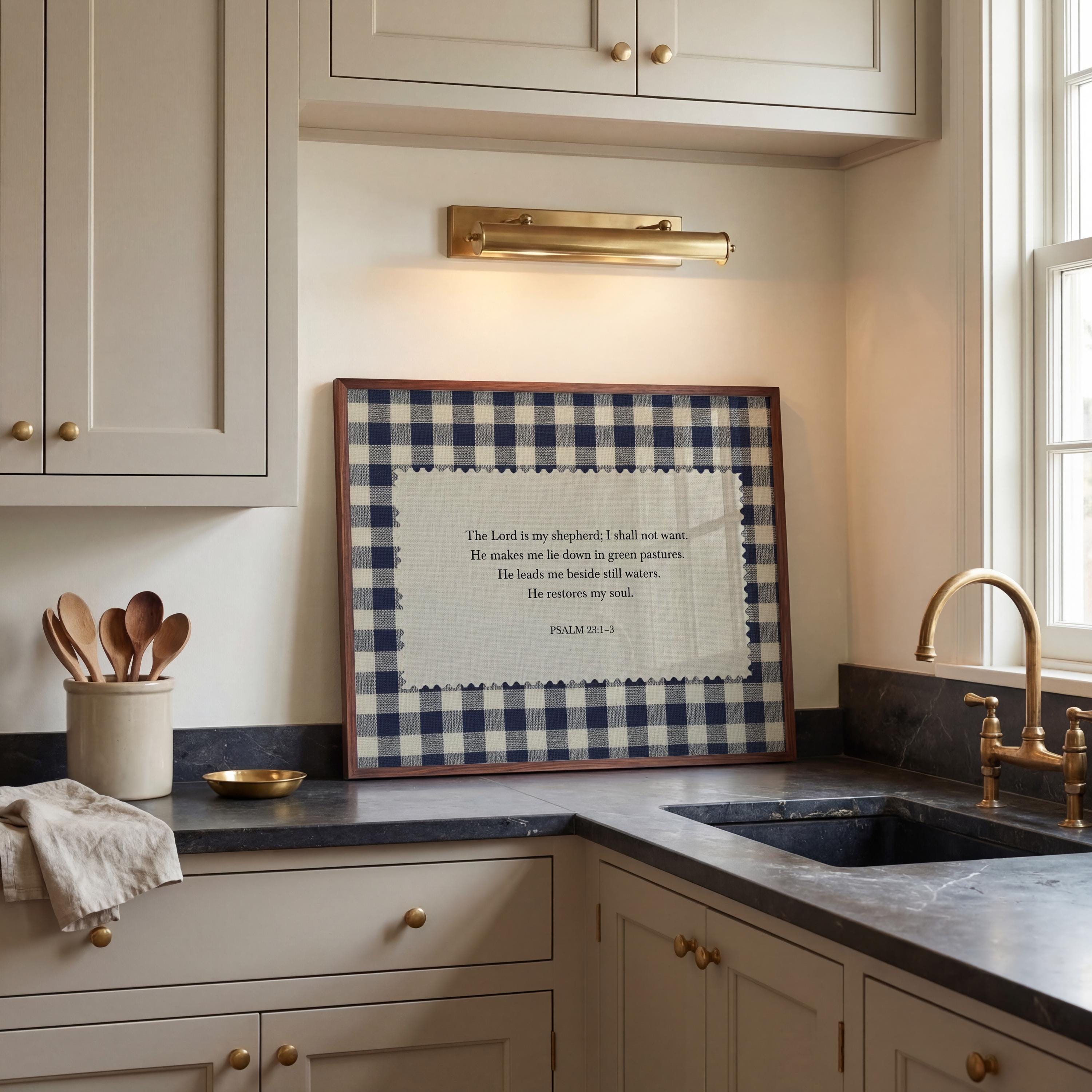 a kitchen counter with a framed Bible verse, a bowl, and a cup. The counter is made of marble and has a sink and cabinets.