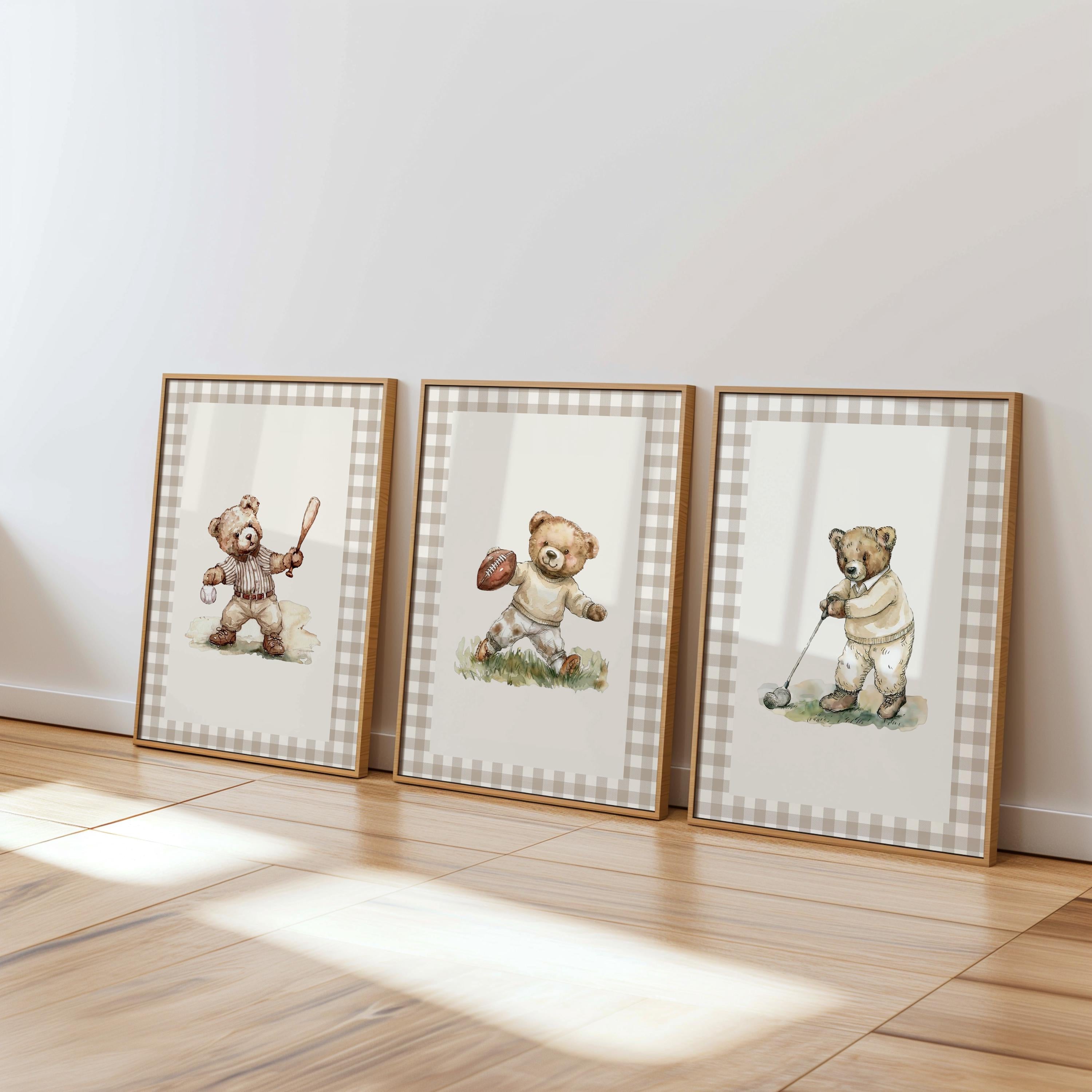 Three framed pictures of teddy bears in various poses, including one holding a baseball, are displayed on a wooden floor against a white wall.
