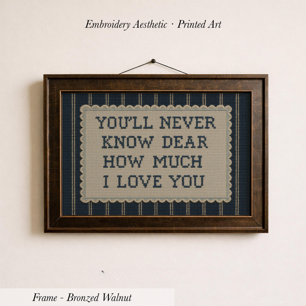 a framed embroidered piece of art with the text "YOU'LL NEVER KNOW DEAR HOW MUCH I LOVE YOU" on it.