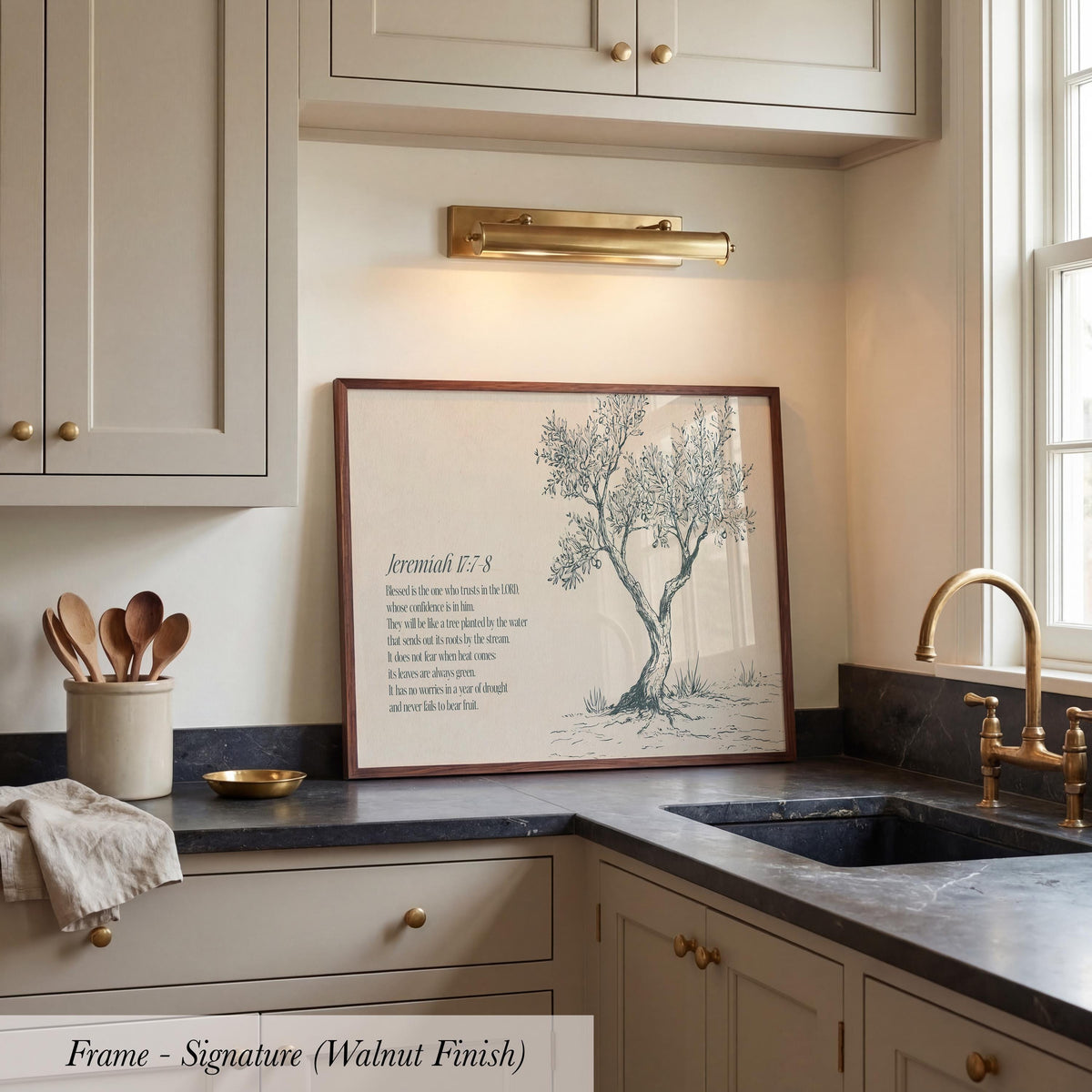 a kitchen counter with a framed print of a tree on it, along with a sink and various kitchen utensils.