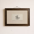 a framed picture of a cowboy riding a horse, with a small piece of paper with a drawing of a cowboy and a horse in the center of the frame.