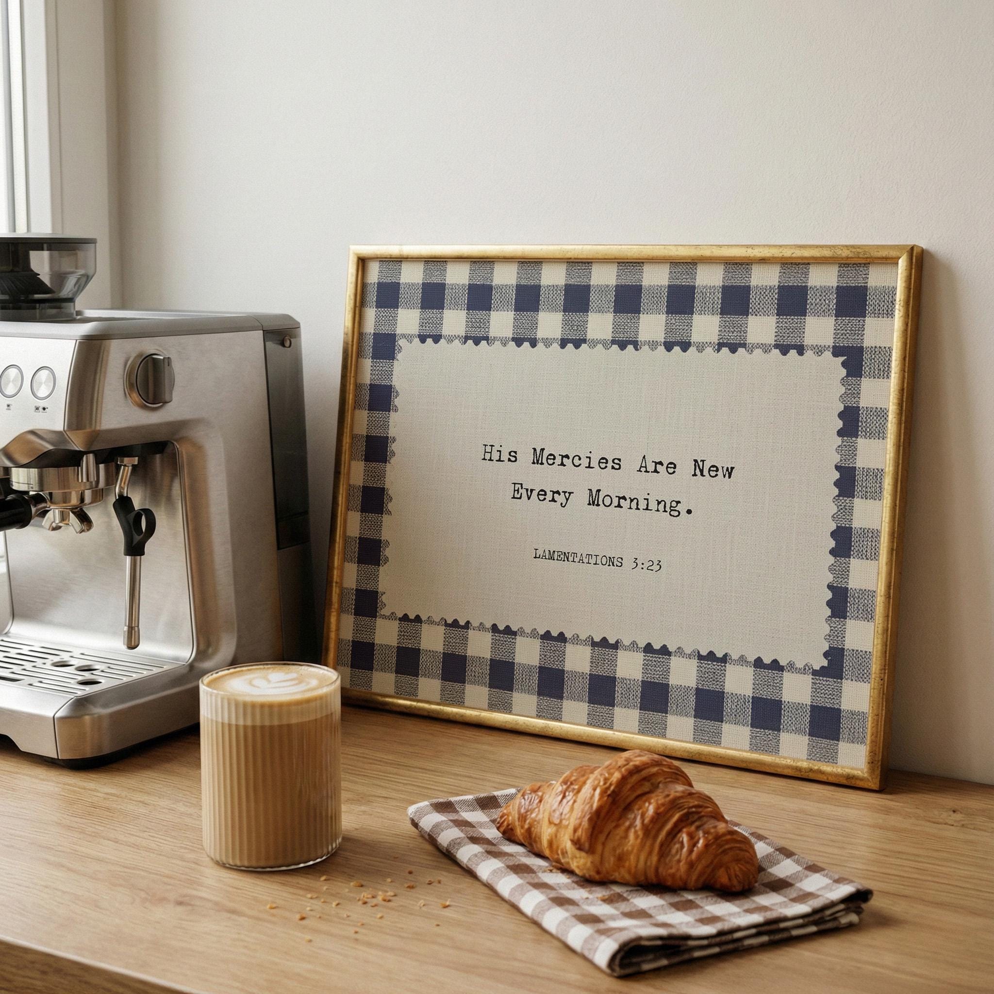 a framed quote on a wooden surface, a croissant on a napkin, and a cup of coffee.