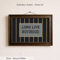 a framed embroidered piece of art with the text "LONG LIVE BOYHOOD" on it.