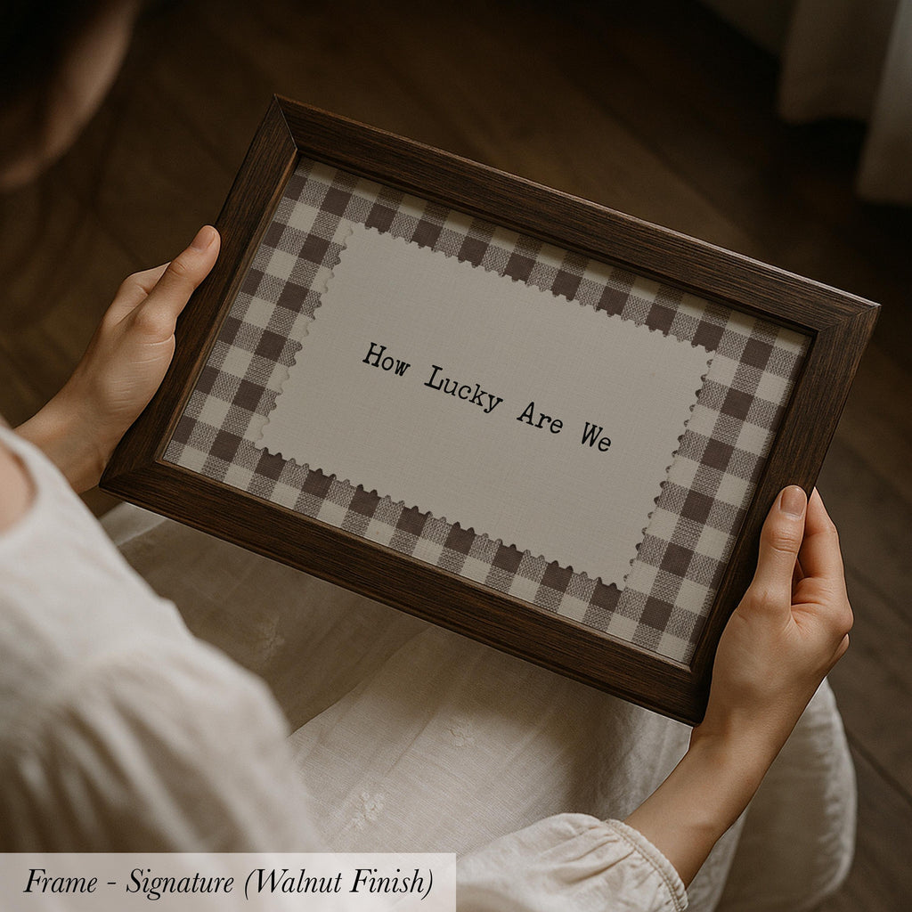 A person is holding a framed picture with the text "How Lucky Are We" on it.