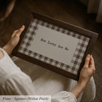 A person is holding a framed picture with the text "How Lucky Are We" on it.
