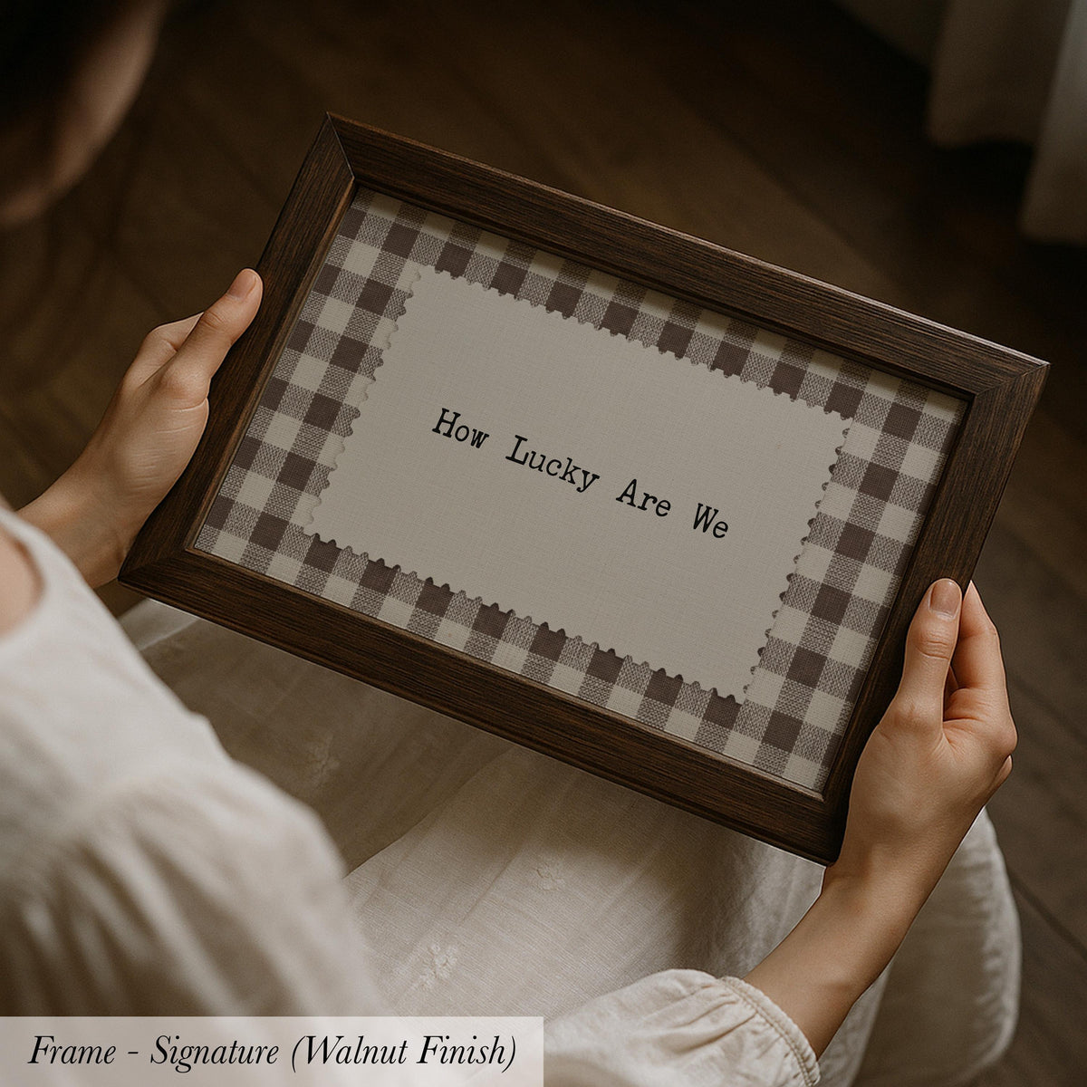 A person is holding a framed picture with the text "How Lucky Are We" on it.