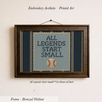 a framed cross-stitch design with the text "ALL LEGENDS START SMALL" and a baseball graphic.