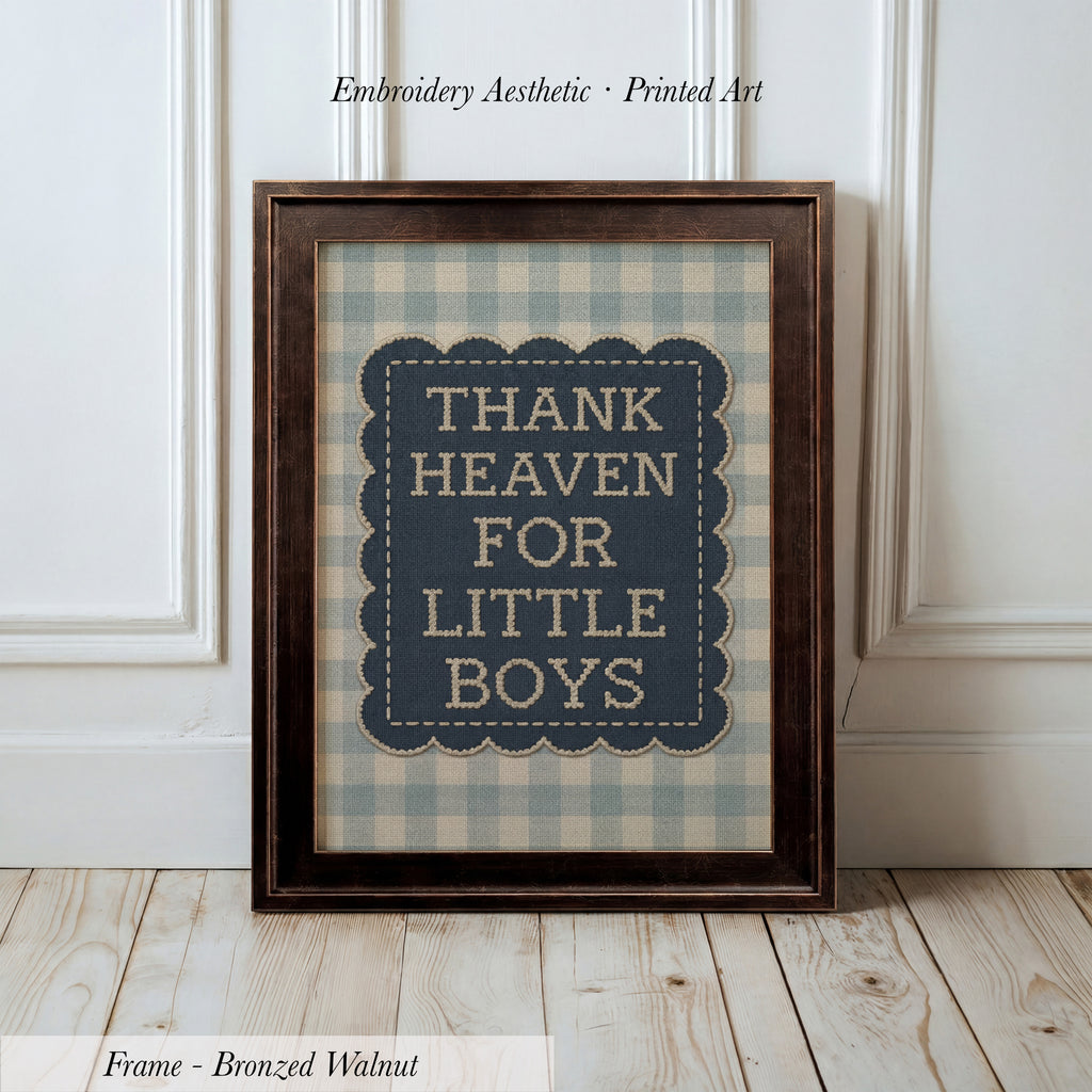 A framed print with the text "THANK HEAVEN FOR LITTLE BOYS" on it, placed on a wooden floor against a white wall.