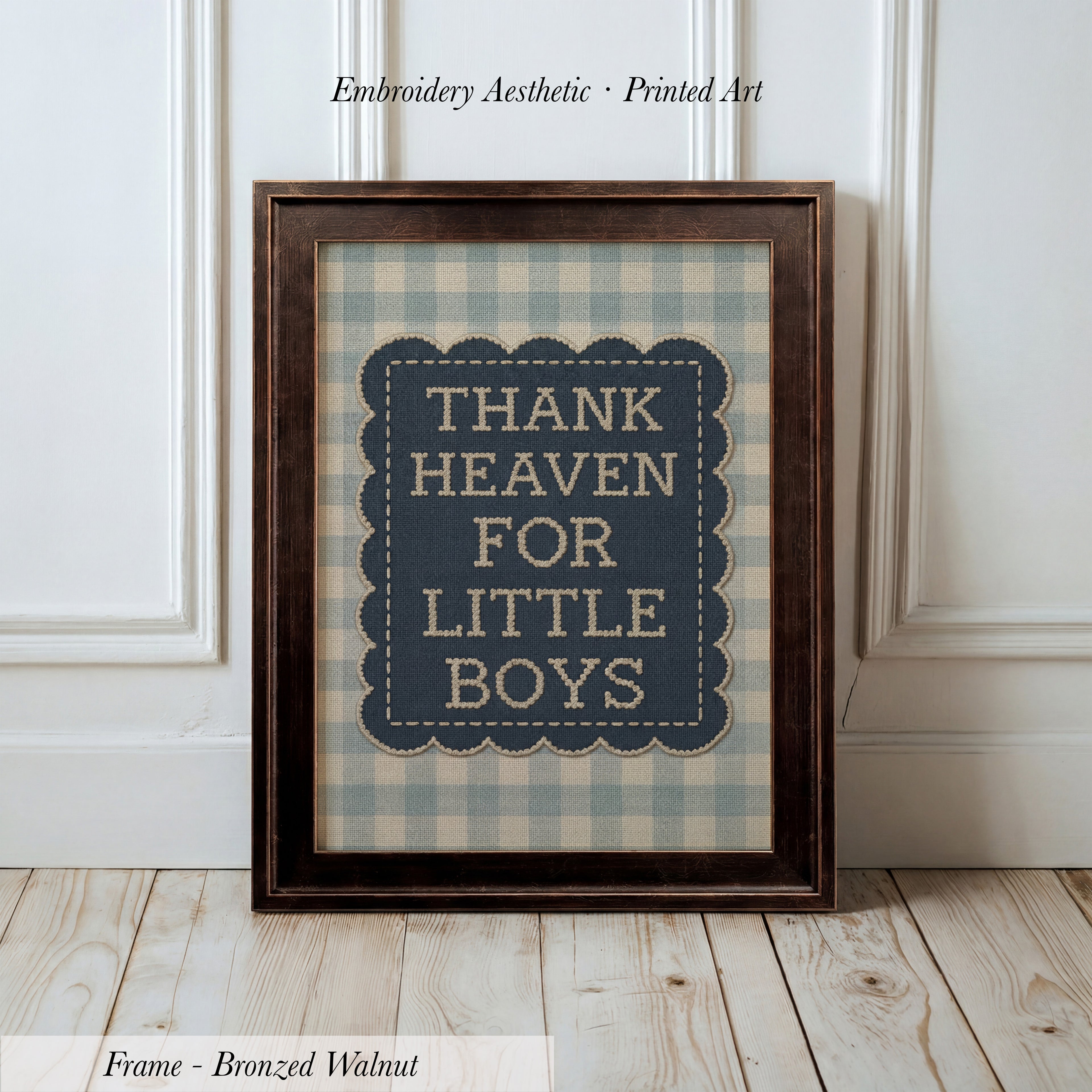 A framed print with the text "THANK HEAVEN FOR LITTLE BOYS" on it, placed on a wooden floor against a white wall.