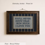 a framed embroidered piece of art with the text "YOU'LL NEVER KNOW DEAR HOW MUCH I LOVE YOU" on it.