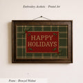 A framed embroidered design with the text "HAPPY HOLIDAYS" on a green and red plaid background.