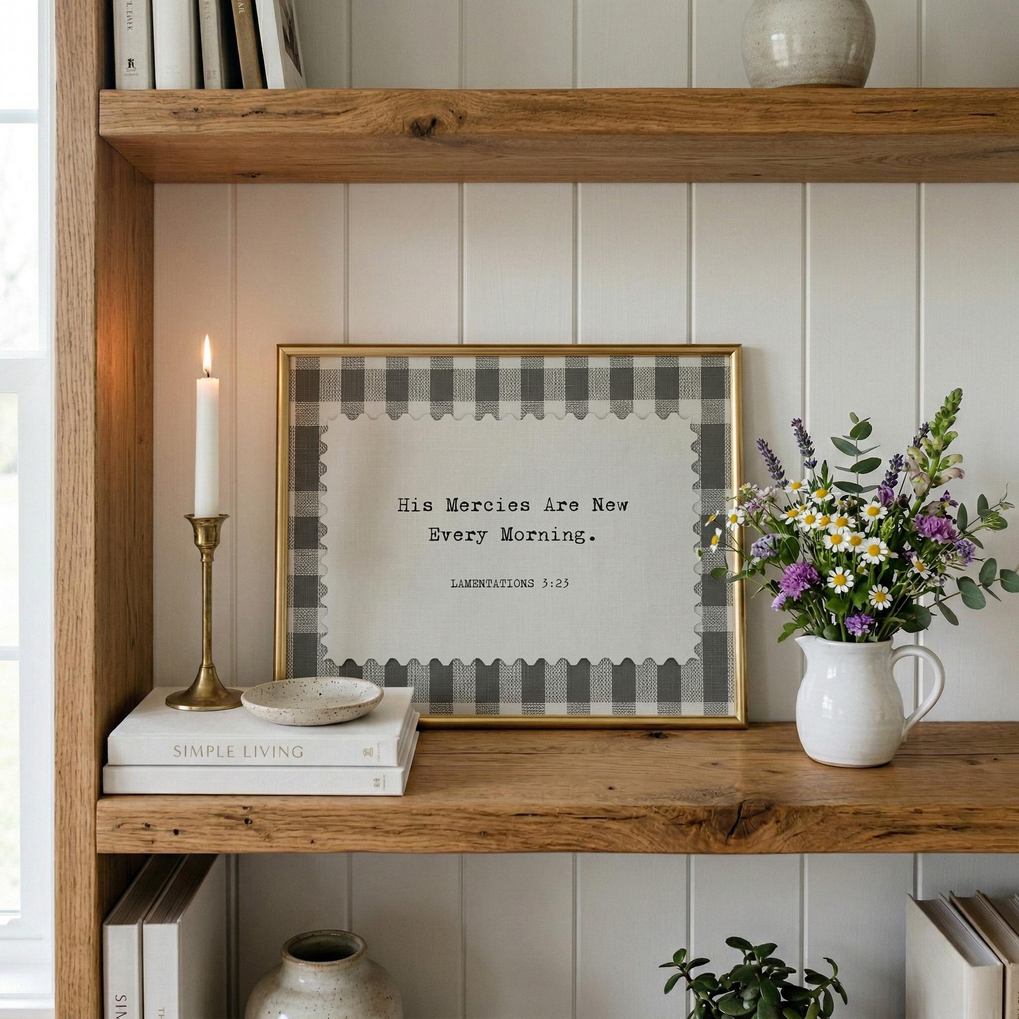 a wooden bookshelf with a framed quote, a white candle, a vase of flowers, and a stack of books.