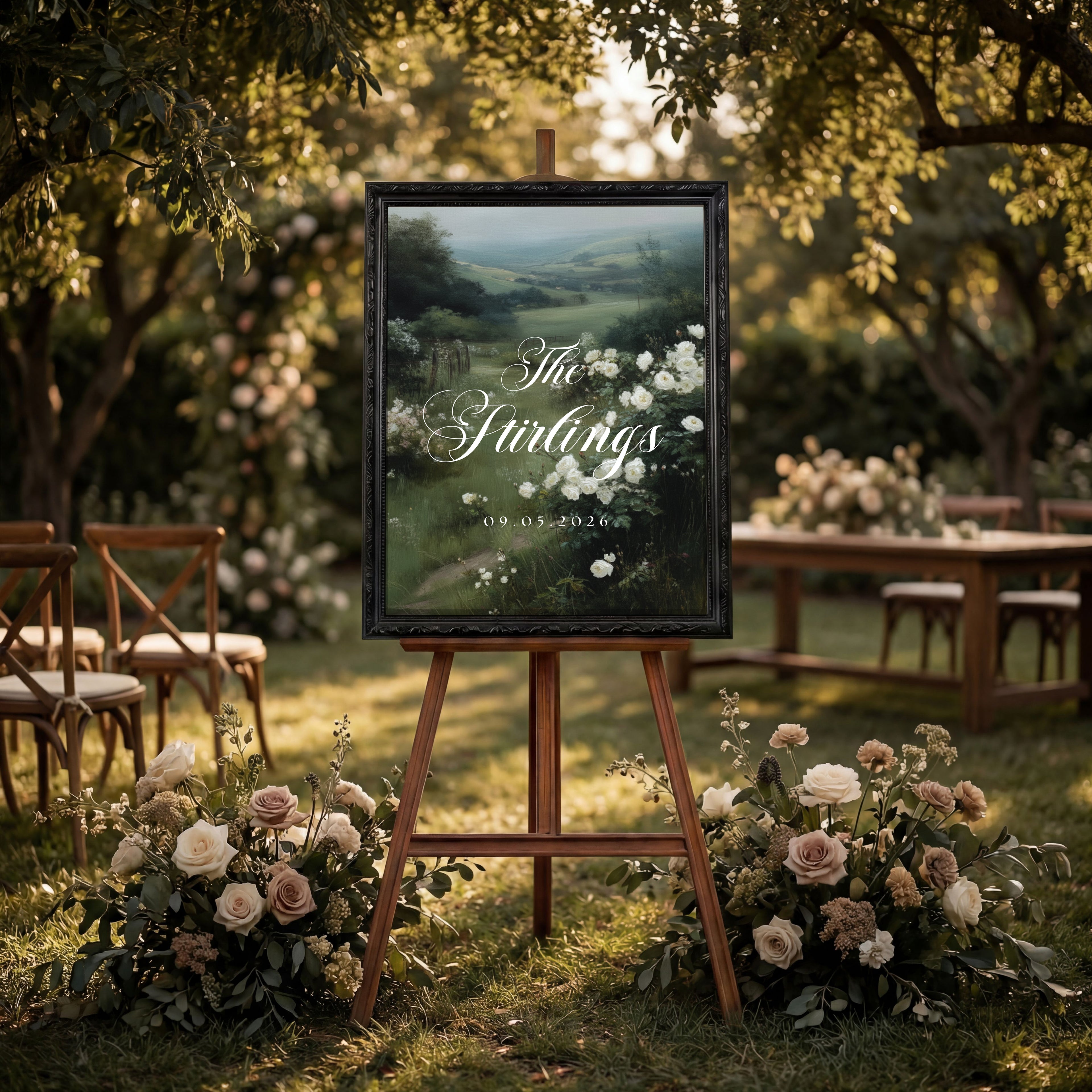 a large outdoor wedding sign with a scenic landscape in the background, surrounded by a garden setting with flowers and wooden furniture.