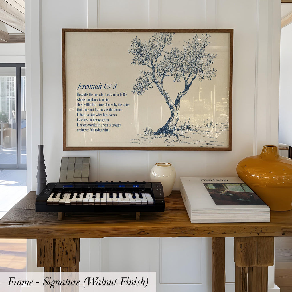 a framed Bible verse with a tree illustration, a keyboard, and a vase on a wooden table.