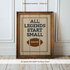 a framed embroidered cross-stitch design with the text "ALL LEGENDS START SMALL" and a football motif.